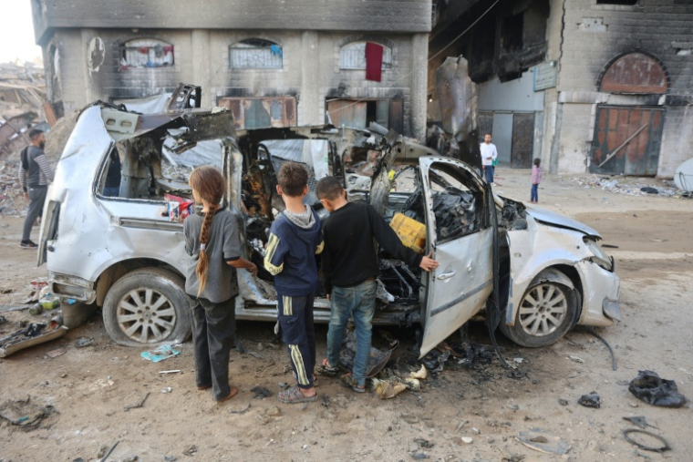 Des enfants palestiniens inspectent une voiture détruite par une frappe israélienne à Gaza-ville, dans le nord de la bande de Gaza, le 22 novembre 2025 ( AFP / Omar AL-QATTAA )