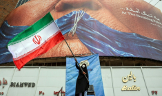 Une femme agite un drapeau iranien devant une affichage anti-américaine faisant référence au président américain Donald Trump et au détroit d'Ormuz à Téhéran, le 5 mai 2026 ( AFP / - )
