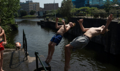 Deux garçons effectuent un salto arrière dans un canal à La Haye, le 26 juin 2026 ( AFP / Lina SELG )