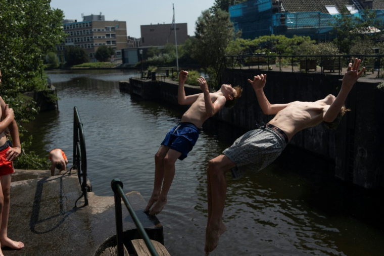 Deux garçons effectuent un salto arrière dans un canal à La Haye, le 26 juin 2026 ( AFP / Lina SELG )