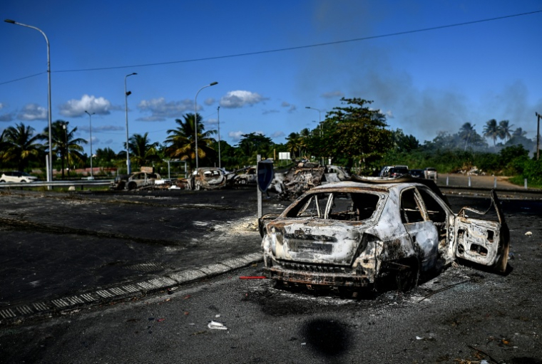 Barrages et carcasses de voitures calcinées sur un rond-point de Petit-Bourg, en Guadeloupe, le 23 novembre 2021  ( AFP / Christophe ARCHAMBAULT )