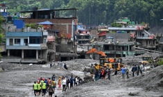 Des pelleteuses dégagent la boue et les décombres après la crue destructrice qui a fait au moins 633 morts à la frontière entre le Népal et la Chine, le 29 août 2026 à Dhunge Bazaar, dans le district népalais de Nuwakot   ( AFP / Arun SANKAR )