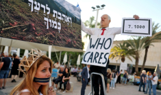 Une manifestante aux côtés d'un homme portant un masque à l'effigie du Premier ministre israélien Benjamin Netanyahu lors d'un rassemblement contre le gouvernement et la guerre à Gaza, le 2 juillet 2026 sur la "Place des Otages" à Tel-Aviv, marquant le millième jour depuis l'attaque du Hamas contre Israël le 7 octobre 2023 ( AFP / Jack GUEZ )