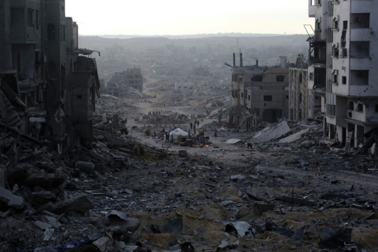 Des Palestiniens passent devant des bâtiments détruits dans la ville de Gaza, le 12 octobre 2025 ( AFP / Bashar TALEB )