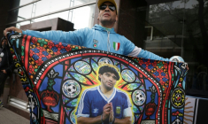 Un fan brandit un drapeau à l'effigie de la légende du football argentin Diego Maradona devant le tribunal à San Isidro en Argentine, le 8 octobre 2026 ( AFP / STRINGER )