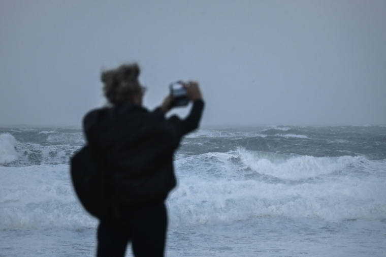 Une personne prend des photos des vagues alors que la tempête Benjamin provoque de fortes rafales de vent à Lacanau, le 23 octobre 2025 en Gironde ( AFP / Philippe LOPEZ )