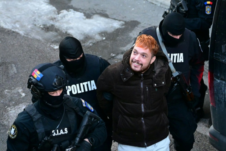 Mohamed Amra escorté par des policiers, le lendemain de son arrestation à Bucarest le 23 février 2025 ( AFP / Daniel MIHAILESCU )