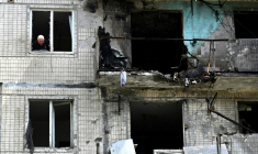 Un habitant à la fenêtre de son appartement dans un immeuble résidentiel endommagé par une frappe de drone russe sur Kiev, le 24 mai 2025 en Ukraine ( AFP / Sergei SUPINSKY )