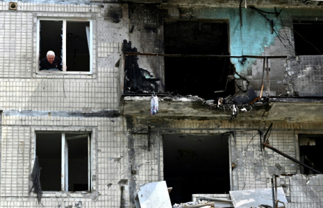 Un habitant à la fenêtre de son appartement dans un immeuble résidentiel endommagé par une frappe de drone russe sur Kiev, le 24 mai 2025 en Ukraine ( AFP / Sergei SUPINSKY )
