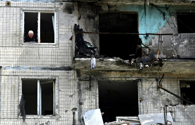 Un habitant à la fenêtre de son appartement dans un immeuble résidentiel endommagé par une frappe de drone russe sur Kiev, le 24 mai 2025 en Ukraine ( AFP / Sergei SUPINSKY )