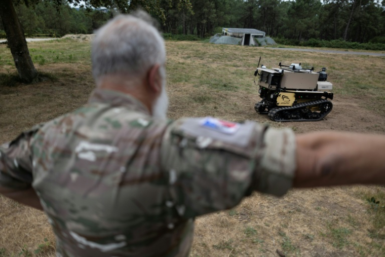 Un militaire observe la progression d'un robot autonome, le 2 juillet à Coëtquidan, dans l'ouest de la France ( AFP / Fred TANNEAU )
