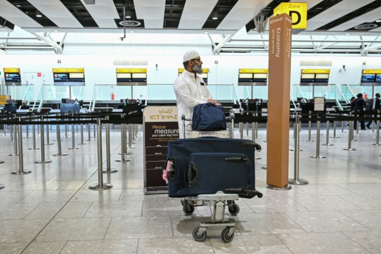 Un homme et ses bagages devant le comptoir d'enregistrement fermé de la compagnie aérienne émiratie Etihad, le 1er mars 2026 à l'aéroport Heathrow de Londres  ( AFP / JUSTIN TALLIS )