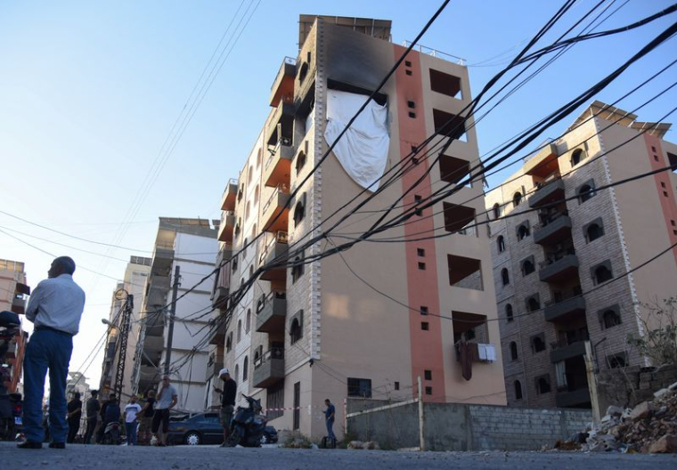 Des personnes se tiennent sur le site touché par une frappe israélienne dans la ville de Tripoli, au Liban