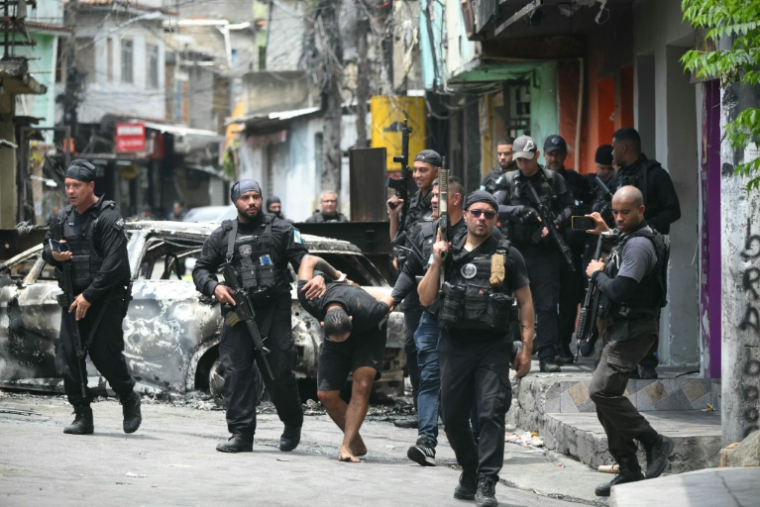 Des policiers escortent un criminel présumé arrêté lors d'une opération dans la favela de Vila Cruzeiro, dans le complexe de Penha, à Rio de Janeiro, le 28 octobre 2025 au Brésil ( AFP / Mauro PIMENTEL )