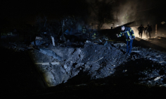 Un pompier ukrainien examine un cratère après une frappe de missile russe qui a touché des habitations à Kiev dans la soirée du 21 octobre 2026 ( AFP / Genya SAVILOV )