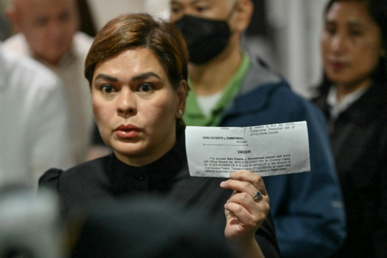 La vice-présidente philippine Sara Duterte brandit le reçu de versement de sa caution, au tribunal en banlieue de Manille, le 5 septembre 2026 ( AFP / Ted ALJIBE )