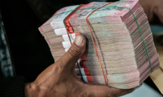 Un homme reçoit une liasse de billets de roupies dans un bureau de change à Jakarta en Indonésie le 4 juin 2026 ( AFP / Yasuyoshi Chiba )