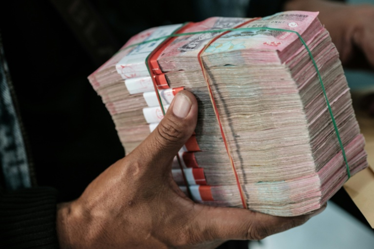 Un homme reçoit une liasse de billets de roupies dans un bureau de change à Jakarta en Indonésie le 4 juin 2026 ( AFP / Yasuyoshi Chiba )