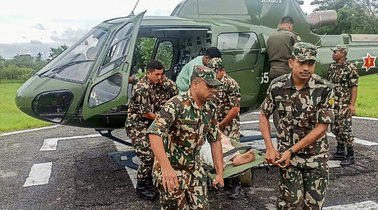 Photo du 5 octobre 2025, prise et diffusée par l'armée népalaise, montrant des militaires transportant une victime évacuée par hélicoptère après des glissements de terrain et des inondations provoqués par de fortes pluies au Népal ( Nepalese Army / - )