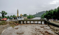 Des villageois (d) se tiennent près d'un pont alors que le niveau des eaux de crue monte dans le district de Buner, dans la province  de Khyber Pakhtunkhwa, le 18 août 2025 au Pakistan ( AFP / Abdul MAJEED )