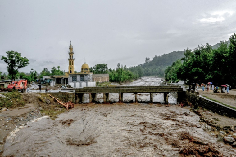 Des villageois (d) se tiennent près d'un pont alors que le niveau des eaux de crue monte dans le district de Buner, dans la province  de Khyber Pakhtunkhwa, le 18 août 2025 au Pakistan ( AFP / Abdul MAJEED )