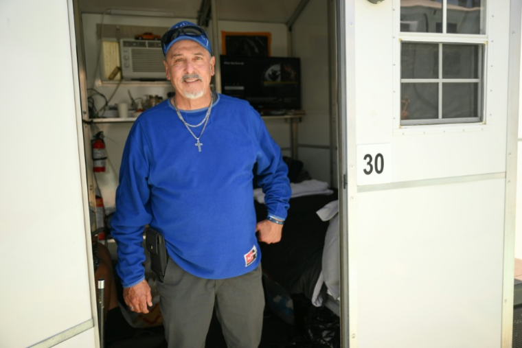 Michael Reyes pose devant la micro-maison en plastique où il est hébergé par l'association Hope the Mission, à Los Angeles, le 1er juin 2026 ( AFP / Patrick T. Fallon )
