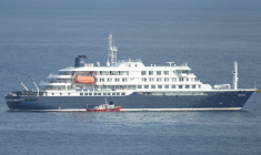 Un bateau-ambulance transportant des membres d'équipage en combinaisons de protection, s'approche du bateau de croisière MV Hondius, au mouillage au large du port de Praia, le 5 mai 2026 au Cap-Vert  ( AFP / - )