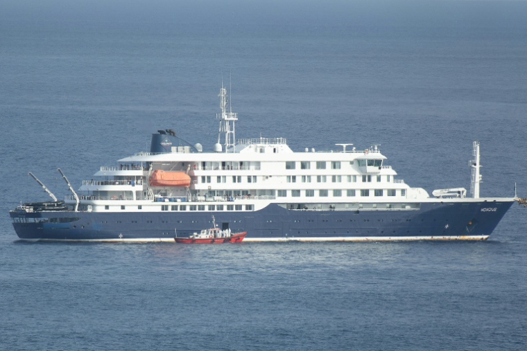 Un bateau-ambulance transportant des membres d'équipage en combinaisons de protection, s'approche du bateau de croisière MV Hondius, au mouillage au large du port de Praia, le 5 mai 2026 au Cap-Vert  ( AFP / - )