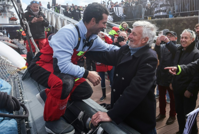 L'aventurier breton Guirec Soudée (G) accueilli à Brest par l'ancien détenteur du record du tour du monde à l'envers, Jean-Luc Van Den Heede (d), le 28 mars 2026 ( AFP / FRED TANNEAU )
