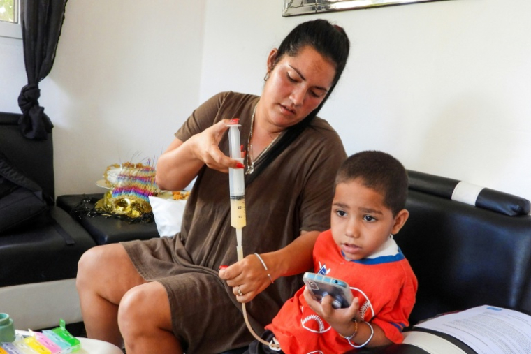 Jessica Rodriguez administre un médicament à son fils Luis Angelo à leur domicile du quartier de Santa Fe à La Havane, le 2 juillet 2025 à Cuba ( AFP / ADALBERTO ROQUE )