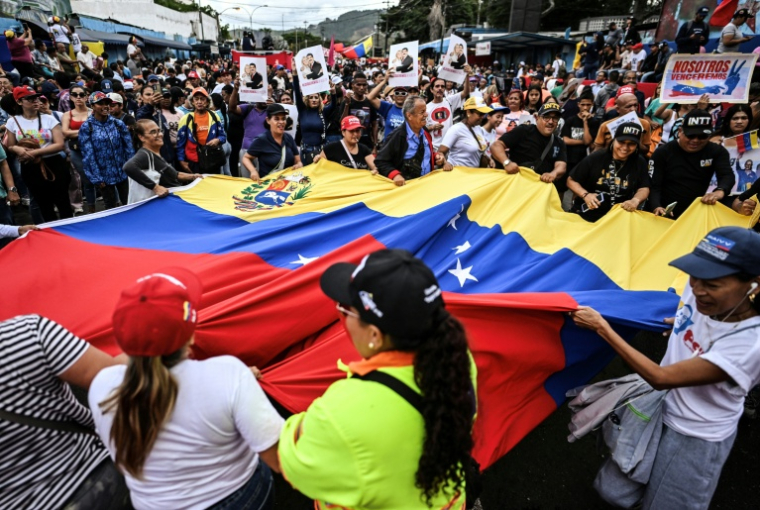 Des manifestants brandissent un drapeau vénézuélien géant lors d'un rassemblement en soutien au président vénézuélien déchu Nicolas Maduro à Caracas, le 10 janvier 2026 ( AFP / Juan BARRETO )