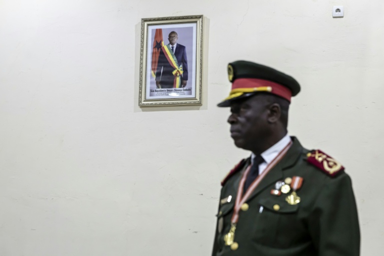 Le général Horta N'Tam devant une photo du président déchu de Guinée-Bissau Umaro Sissoco Embalo durant la cérémonie l'investissant comme dirigeant de la transition, à Bissau le 27 novembre 2025, au lendemain d'un coup d'Etat militaire ( AFP / PATRICK MEINHARDT )