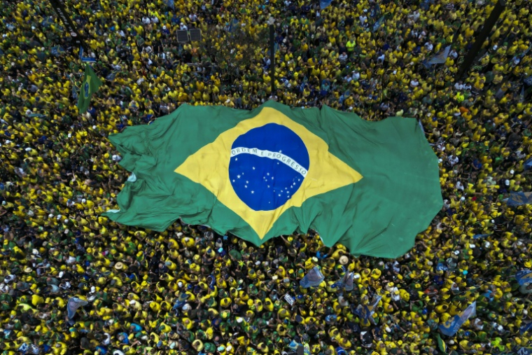 Des partisans de Flavio Bolsonaro, candidat du Parti libéral (PL) à la présidentielle, brandissent un immense drapeau brésilien lors d'un rassemblement à São Paulo, le 18 octobre 2026 au Brésil, avant le second tour de l'élection ( AFP / Miguel SCHINCARIOL )