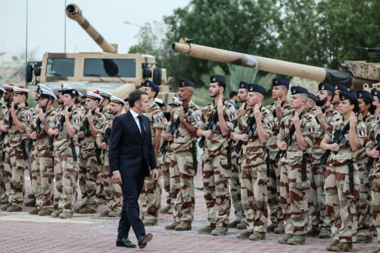 Le président français Emmanuel Macron passe en revue les troupes sur une base militaire près d'Abou Dhabi, le 21 décembre 2025 ( AFP / Ludovic MARIN )