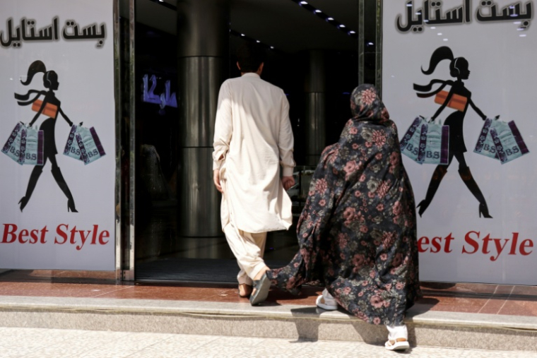 Un homme et une femme entrent dans un centre commercial, le 1er juillet 2026 à Hérat, dans l'ouest de l'Afghanistan  ( AFP / Mohsen KARIMI )
