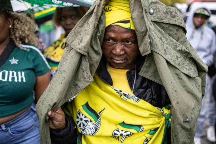 Un manifestant se protège de la pluie à Johannesburg le 21 mars 2026. ( AFP / EMMANUEL CROSET )