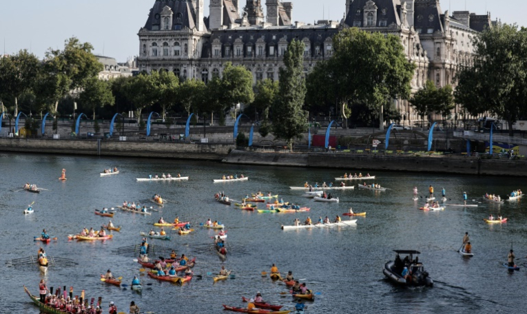 Des kayaks, des paddles et des barques naviguent sur la Seine, avec l'Hôtel de Ville de Paris en arrière-plan, pour marquer le premier anniversaire des Jeux olympiques de Paris 2024, le 26 juillet 2025 ( AFP / STEPHANE DE SAKUTIN )