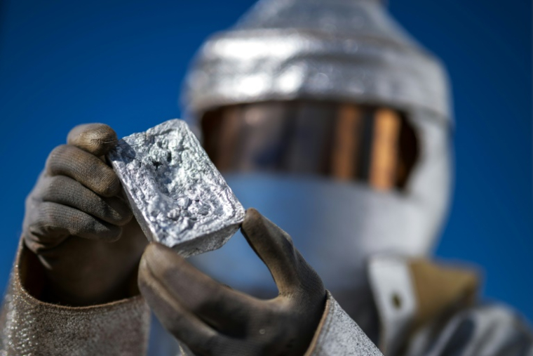 Un ingénieur métallurgique en tenue de protection montre un lingot d'aluminium durant la présentation d'un four solaire de l'entreprise Panatère à La Chaux-de-Fonds, en Suisse, le 2 octobre 2025  ( AFP / Fabrice COFFRINI )