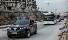Un bus transportant des combattants kurdes quitte le quartier majoritairement kurde de Cheikh Maqsoud à Alep, dans le nord de la Syrie, sous escorte des forces de sécurité, le 10 janvier 2026 ( AFP / OMAR HAJ KADOUR )