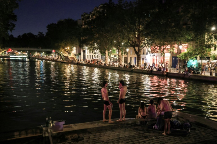 Des jeunes cherchent de la fraîcheur près du canal Saint-Martin, le 25 juin 2026 à Paris ( AFP / Ludovic MARIN )