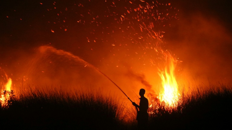 Cette photo prise le 11 août 2026 montre la silhouette d'un villageois tentant d'éteindre un incendie de forêt à Palangkaraya, dans le centre de l'Indonésie ( AFP / REINA )