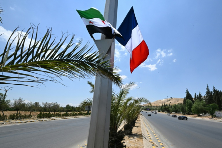 Des drapeaux français et syrien le long de la route menant à l'aéroport de Damas, le 6 juillet 2026, en amont d'une visite du président français Emmanuel Macron en Syrie ( AFP / LOUAI BESHARA )