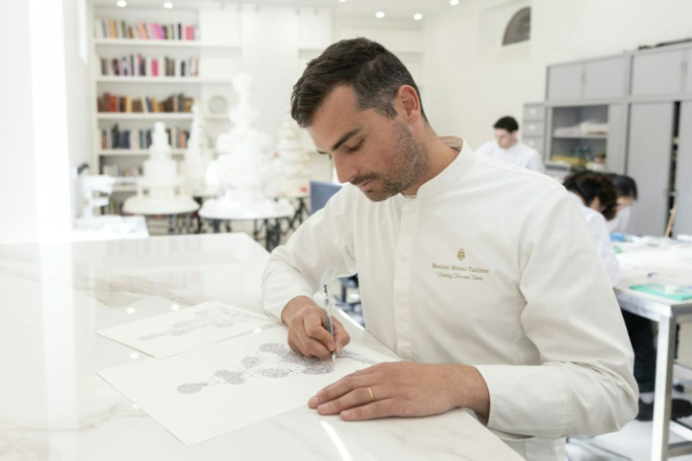 Le chef pâtissier français Bastien Blanc-Tailleur dessine le projet d'un gâteau de mariage dans son atelier de Saint-Rémy-lès-Chevreuse, dans les Yvelines, le 10 avril 2026 ( AFP / Thomas SAMSON )