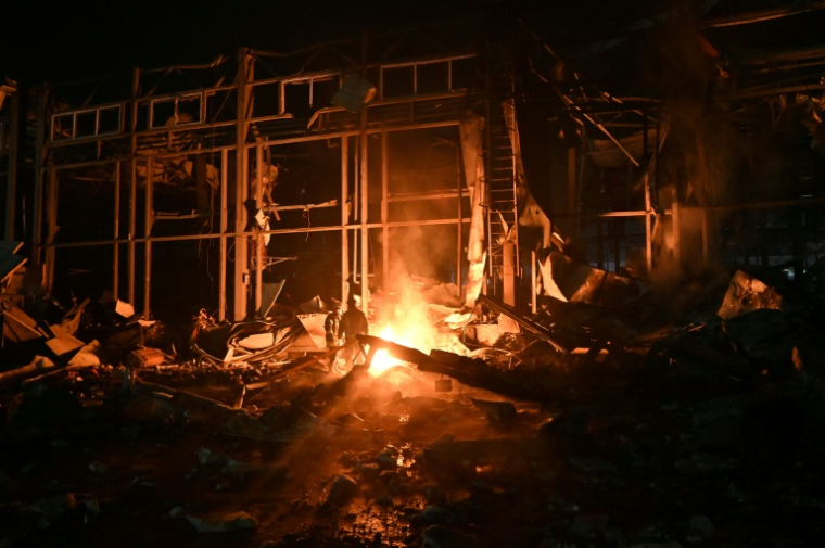 Des pompiers luttent contre un incendie provoqué par un bombardement russe sur un entrepôt de la compagnie des postes Nova Pochta dans un village près de Kharkiv, le 13 janvier 2026 en Ukraine ( AFP / SERGEY BOBOK )