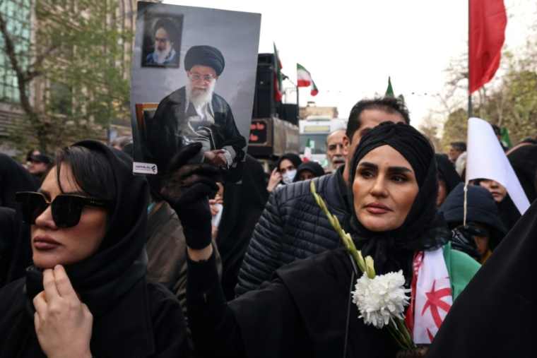Une femme porte un portrait de l'ayatollah Ali Khamenei pendant les funérailles de membres des forces de sécurité, à Téhéran le 14 janvier 2026 ( AFP / ATTA KENARE )
