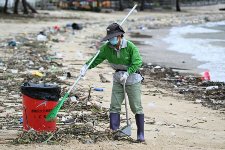 Un ouvrier nettoie la plage de Silver Mine après le passage du super typhon Ragasa près de Hong Kong, le 25 septembre 2025 ( AFP / Peter PARKS )