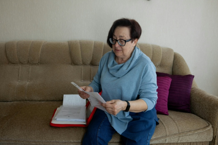 Tetiana Zaïtseva regarde des documents relatifs à la mort de son fils Artem, à Kryvyï Rig en Ukraine, le 20 avril 2026 ( AFP / Tetiana DZHAFAROVA )