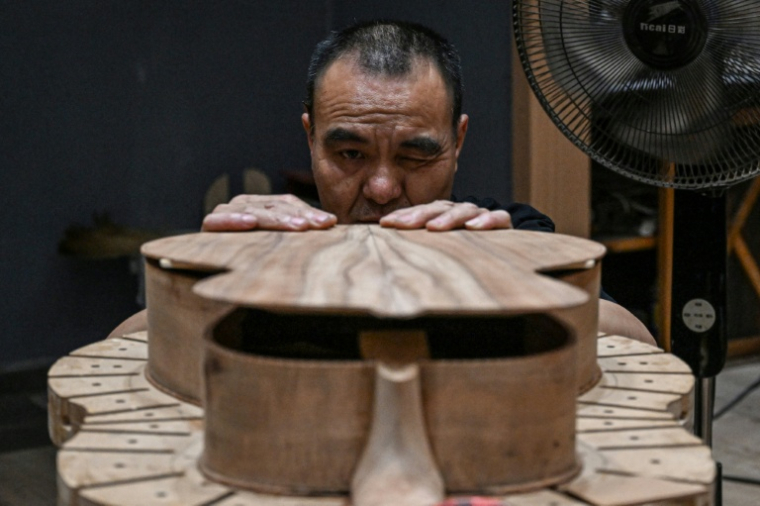 Cette photo prise le 27 juillet 2026 montre un ouvrier fabriquant une guitare dans un atelier de lutherie à Zheng'an, dans la province du Guizhou, dans le sud-ouest de la Chine. ( AFP / Jade GAO )
