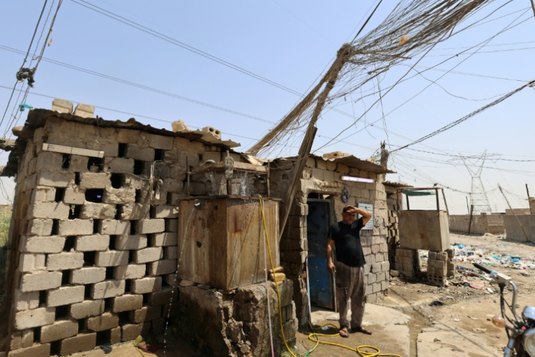 Un électricien fait une pause dans son travail sur un générateur, à Diwaniyah, dans le sud de l'Irak, le 10 août 2025 ( AFP / AHMAD AL-RUBAYE )