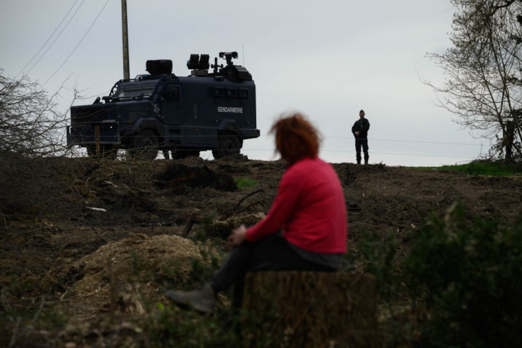 Un manifestant assis devant des policiers tandis que d'autres occupent des arbres pour protester contre le projet d'autoroute A69, à Saix le 22 février 2024. ( AFP / ED JONES )